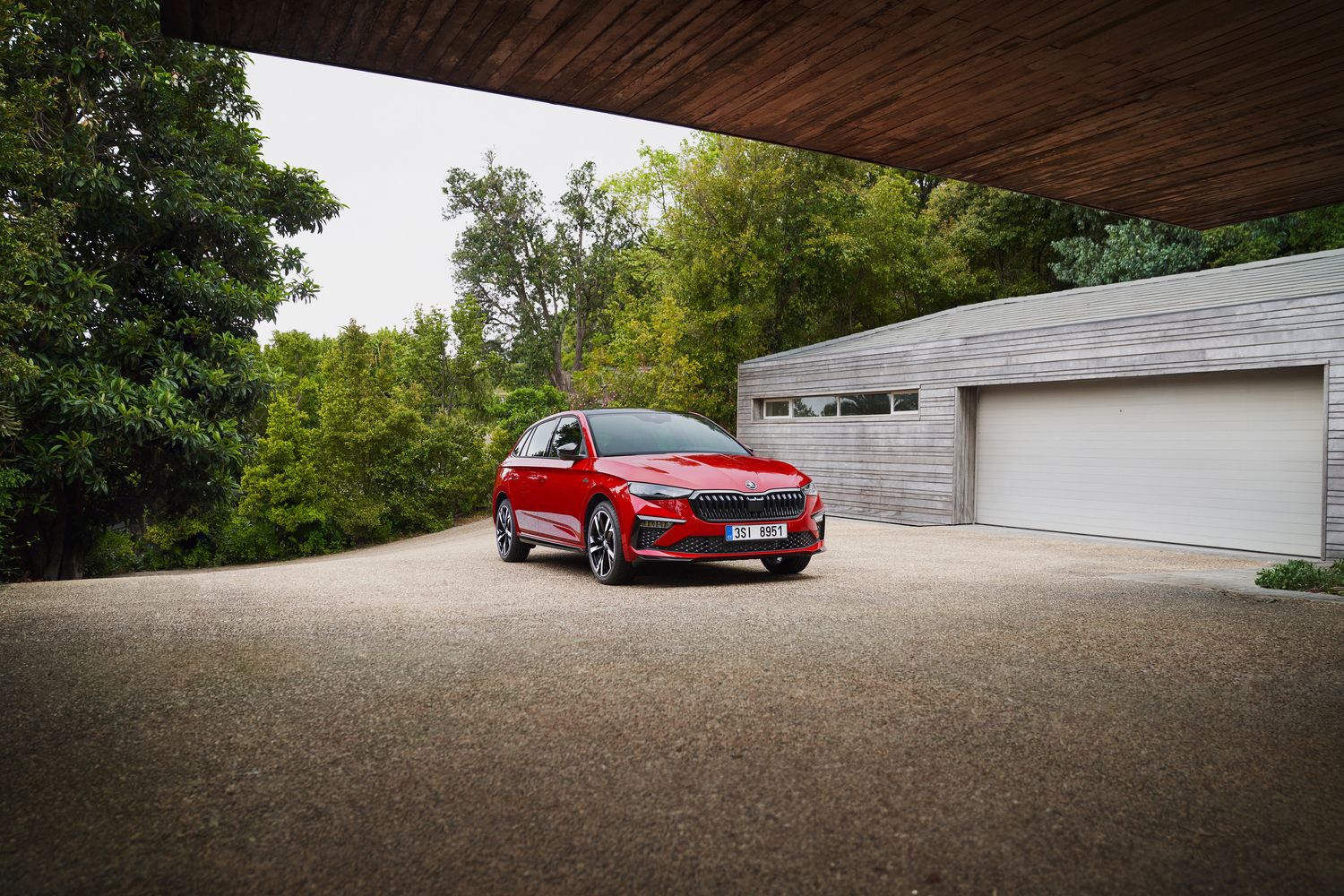 Front view of the new Skoda Scala, in red. Parked by a home garage.