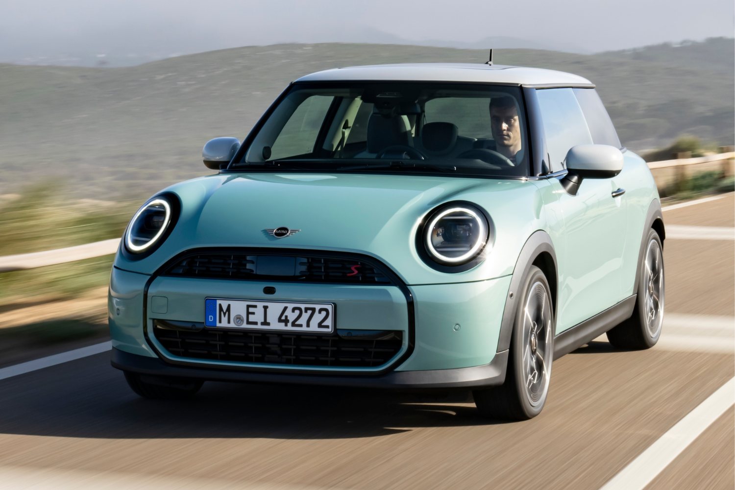 Front view of a mint green MINI cooper driving.