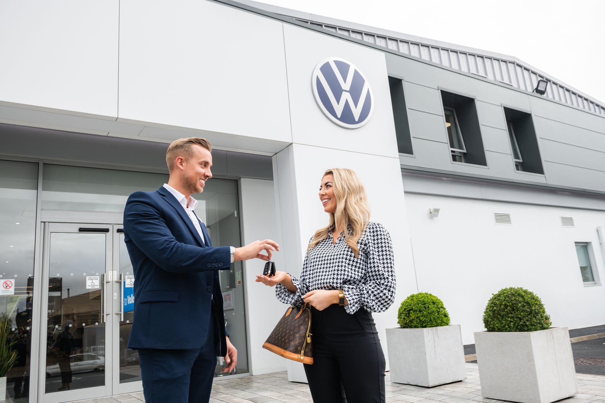 Volkswagen Service Advisor hands over keys to happy customer after service