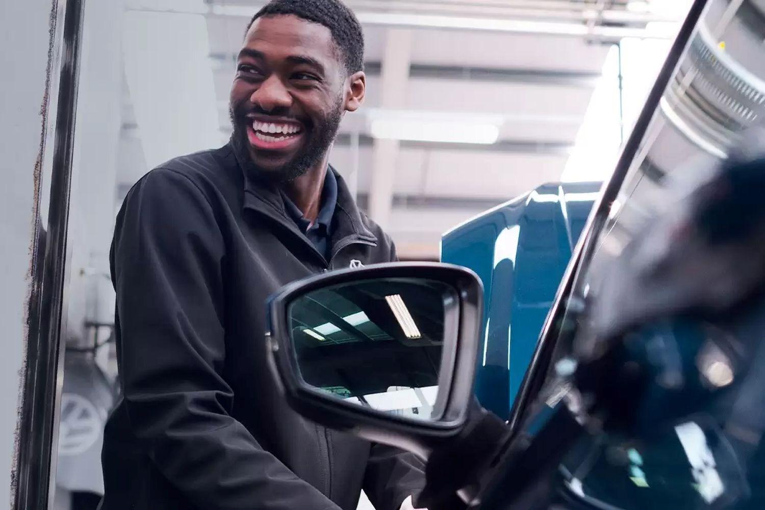 Volkswagen Service Specialist smiles while checking under the hood of a Volkswagen Tiguan during service at the Volkswagen Approved Accident Repair Centre, Agnew Volkswagen Mallusk