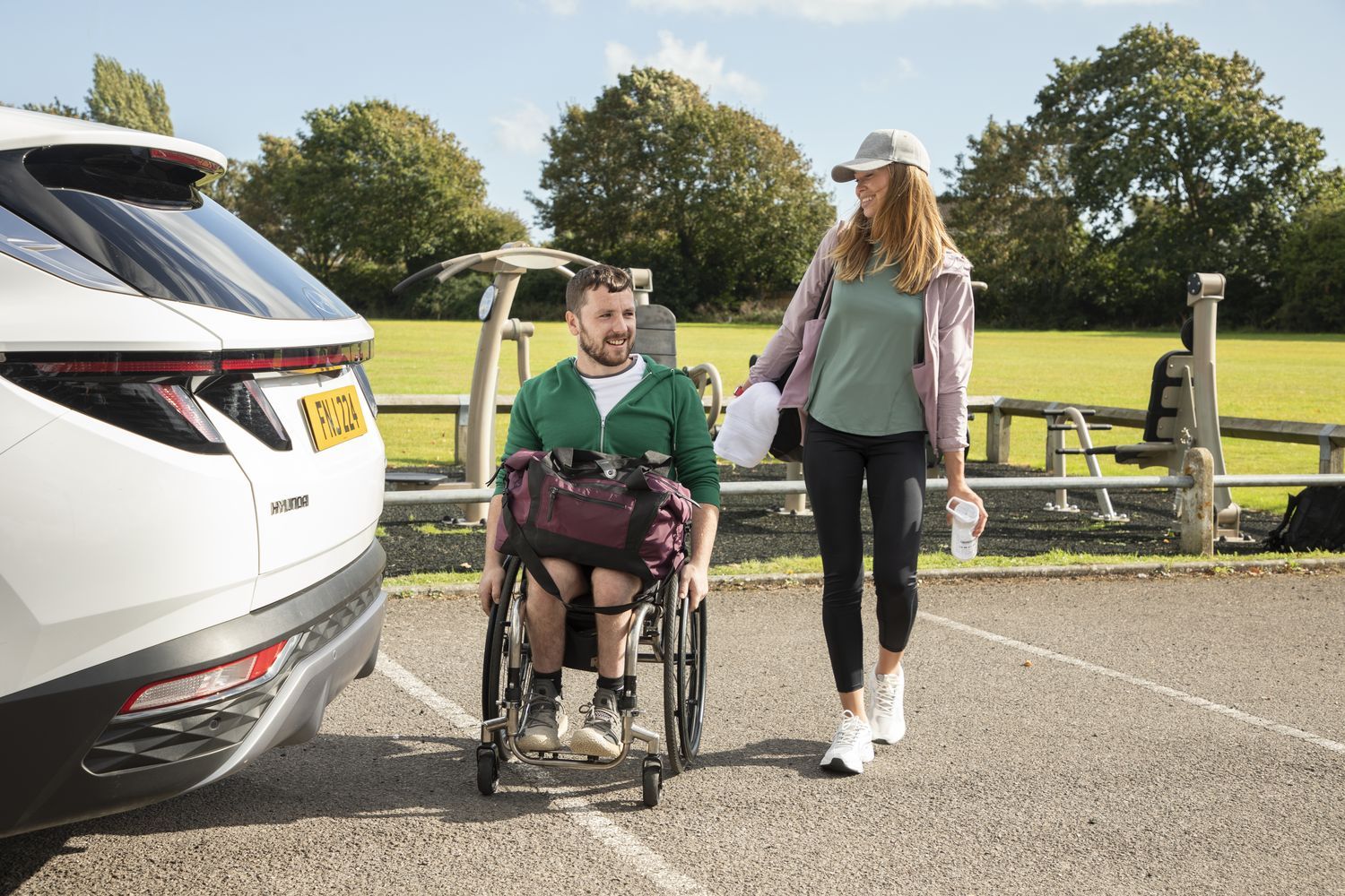 Person in wheelchair talks to friend at the back of their Motability car