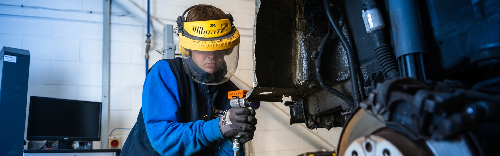 Agnew Repair Centre Technician wearing protective equipment sands a MINI vehicle during repair and maintenance work.