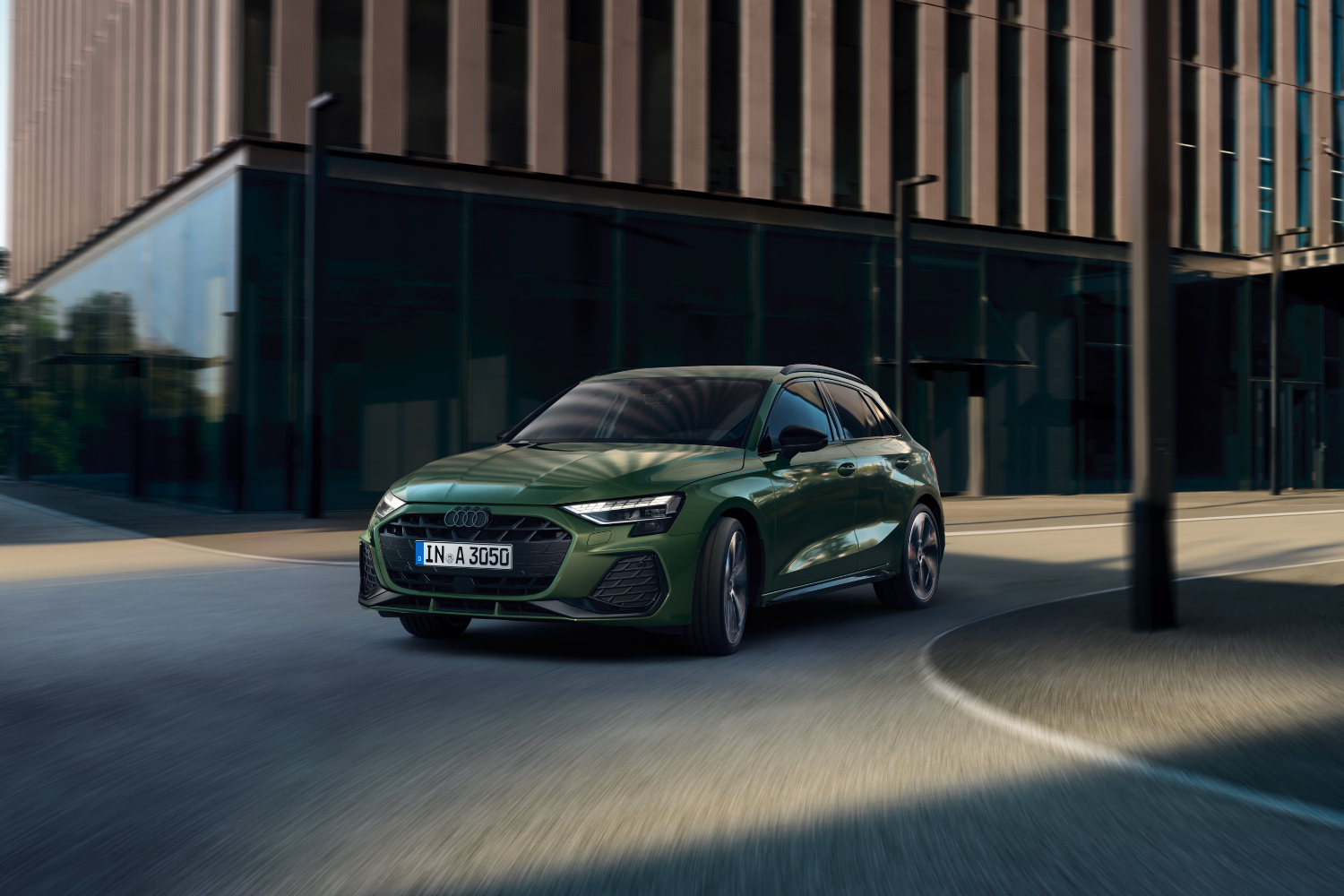 New Audi A3, available at Belfast and Portadown Audi, in green driving on residential street.