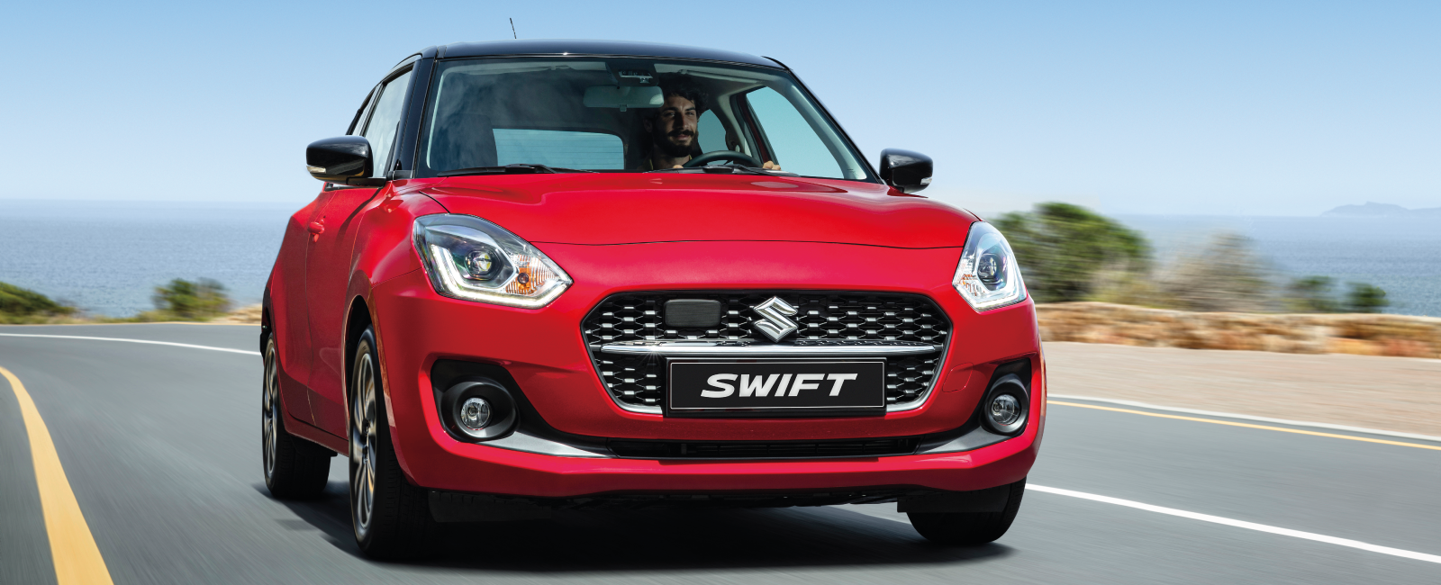 Man driving red Suzuki Swift on the road