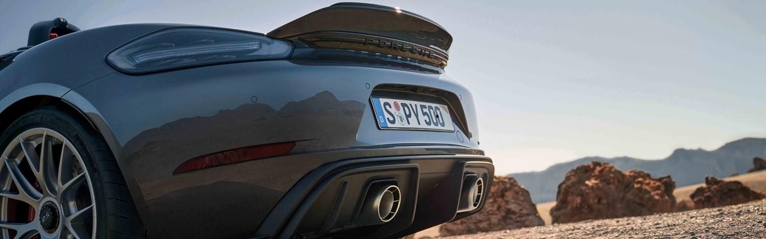 Close-up of the rear of a new Porsche 911 parked in a desert with large red rocks