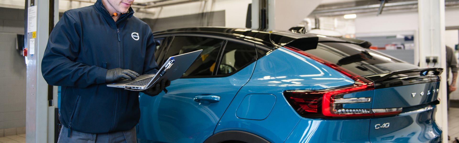Agnew Belfast Volvo mechanic inspects new Volvo C40 Recharge with laptop at Volvo repair centre in Belfast, Northern Ireland for routine maintenance