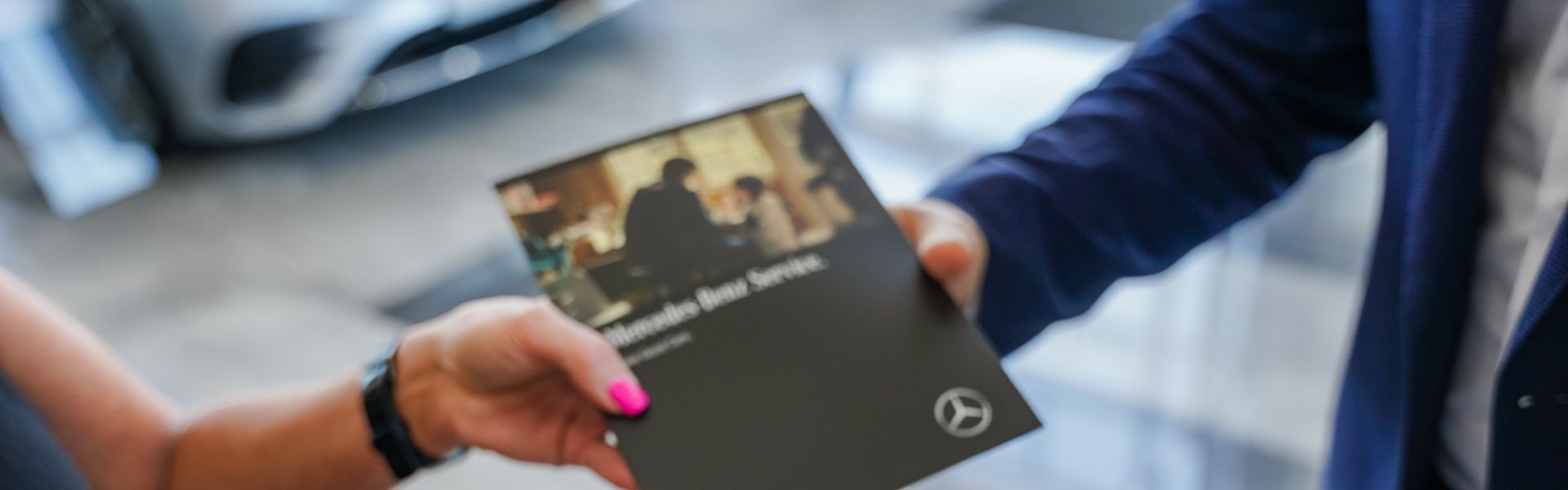 Mercedes-Benz Finance Specialist hands over Mercedes-Benz Service booklet to customer