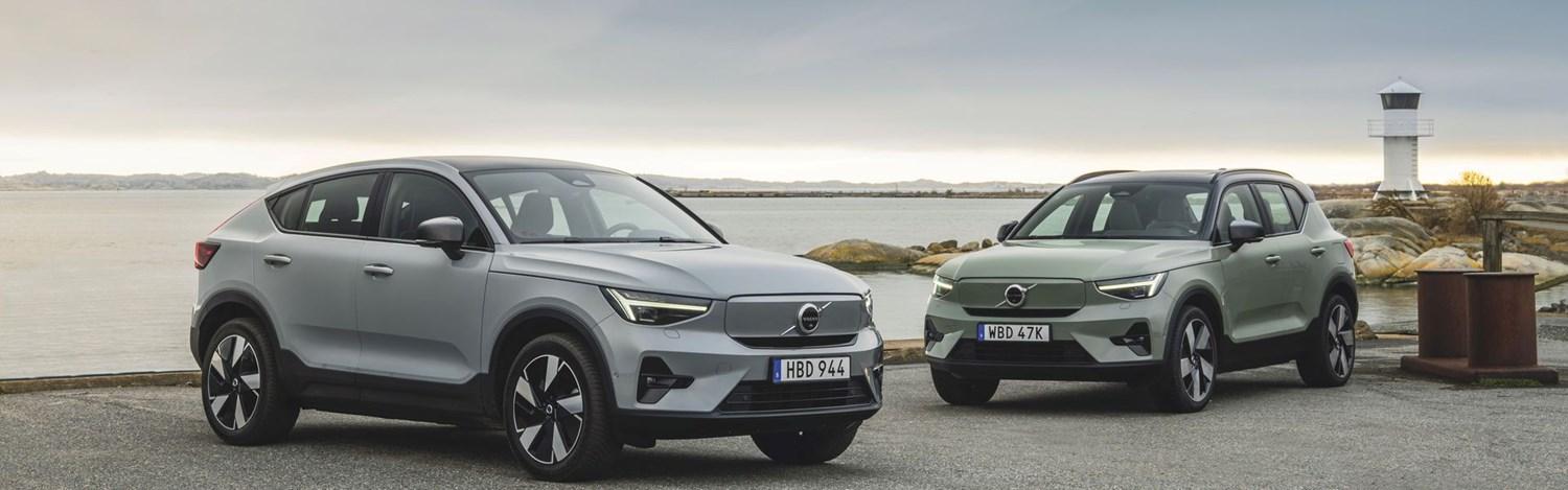 The latest grey Volvo C40 Recharge and Volvo XC40 Recharge parked in front of the sea with white lighthouse behind