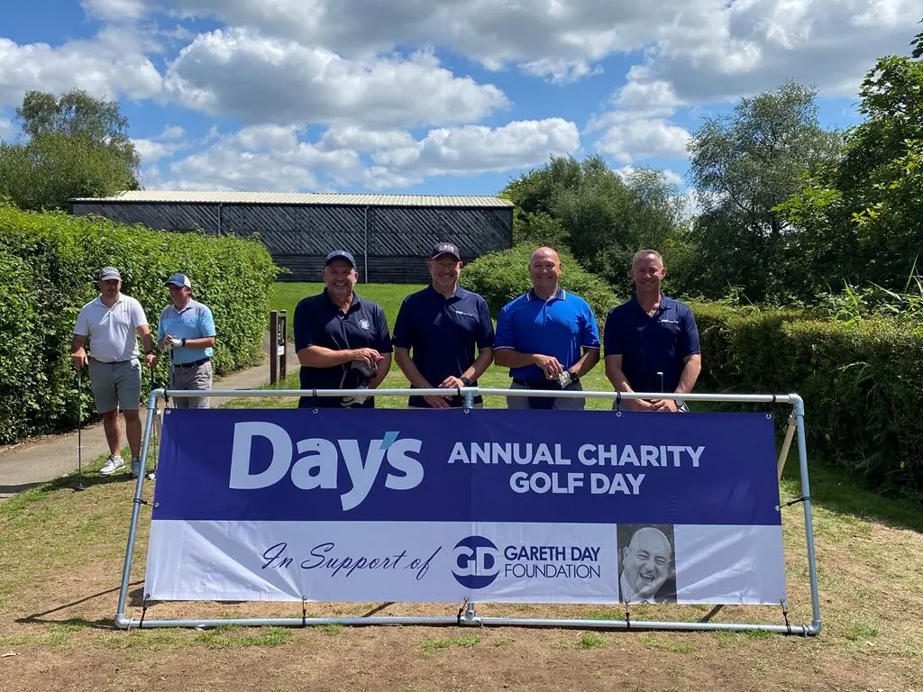 4 Men stood in front of Day's Annual Charity Golf Day banner