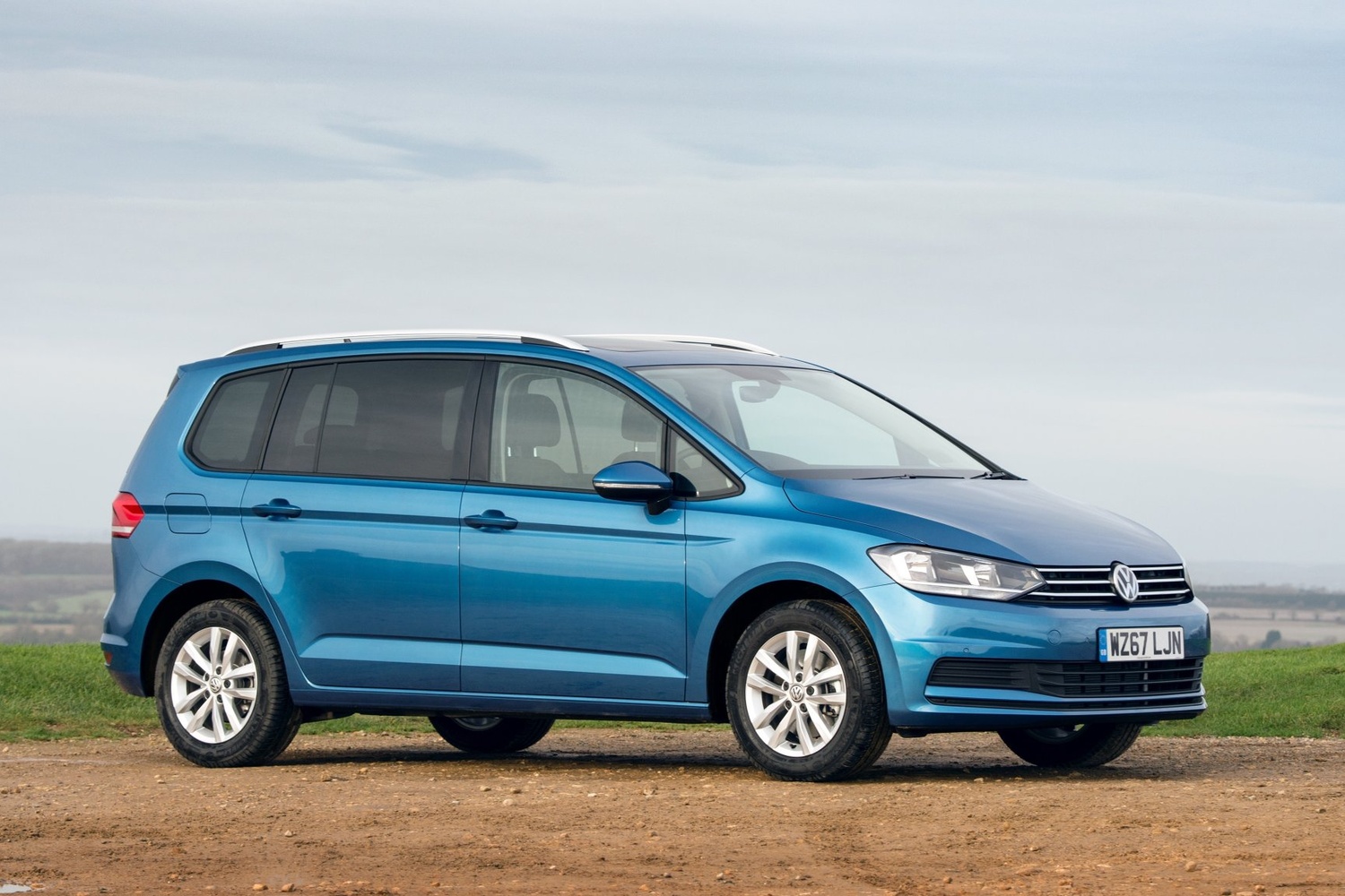 Side view of the new Volkswagen Touran in blue, parked at the top of a hill