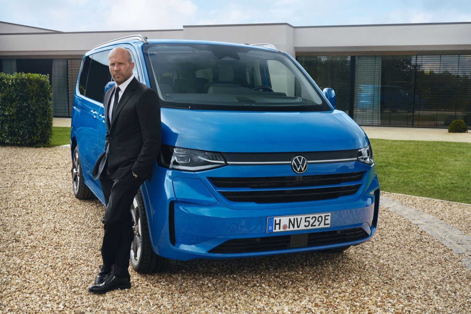 Jason Statham staning next to the all-new Transporter Shuttle (2025) in blue
