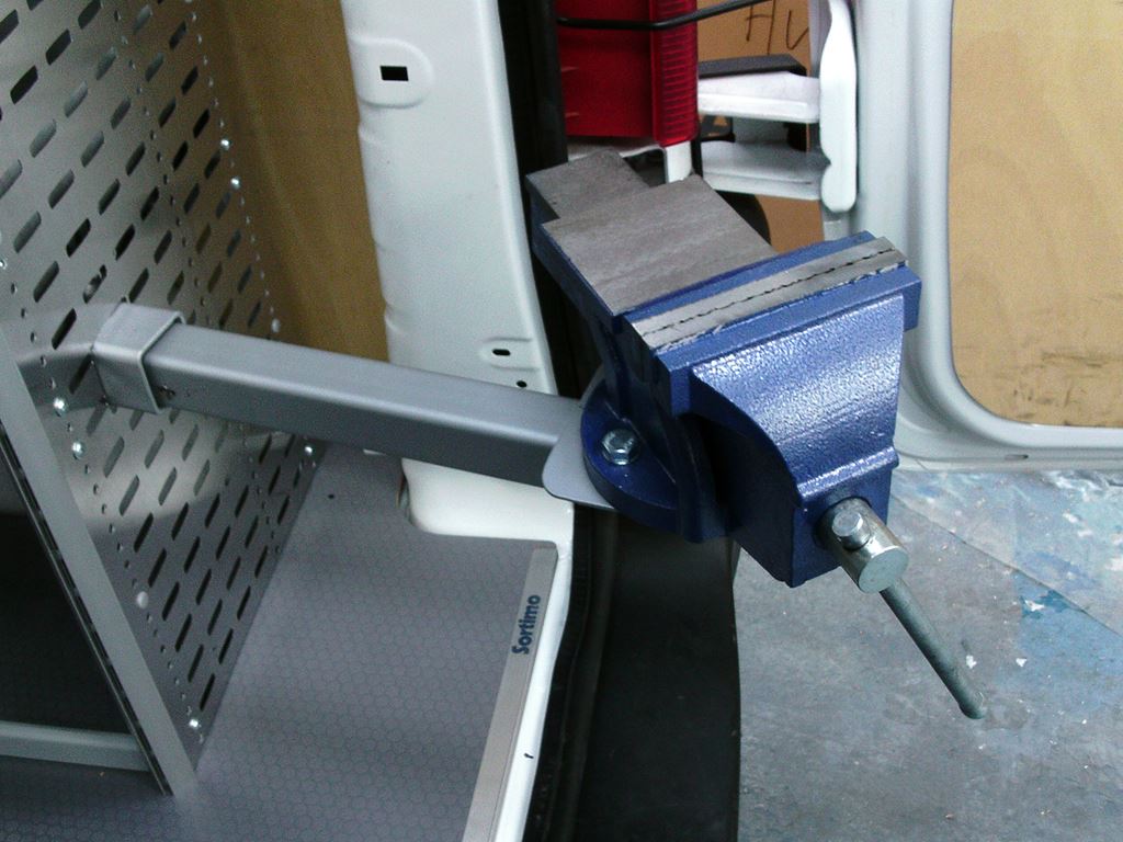 Heavy-duty bench vice mounted to a swing-out arm inside a work van.