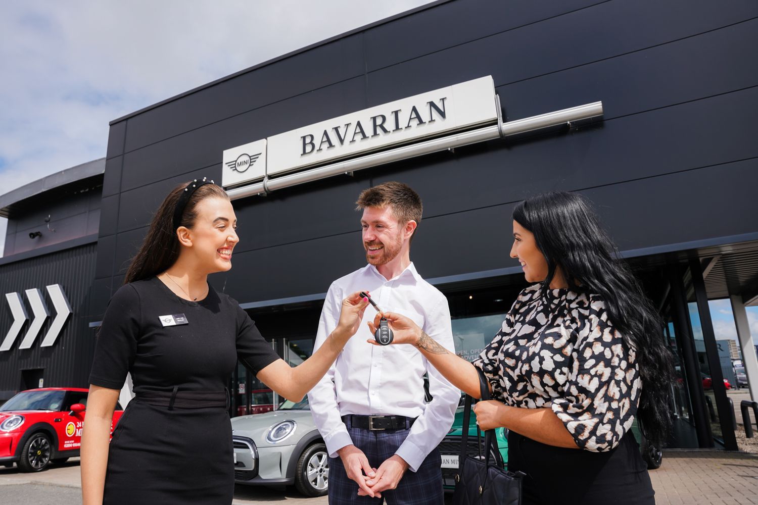 Bavarian MINI Sales Specialist hands over keys to customers new MINI outside of the Bavarian MINI showroom.
