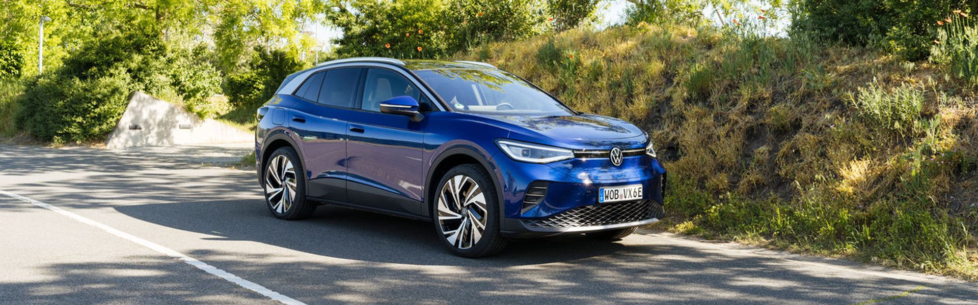 Front and side view of the new Volkswagen ID.4 in blue, driving along a country road