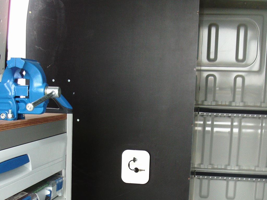 Van interior showing bench vice on a worktop and a lockable access hatch panel.