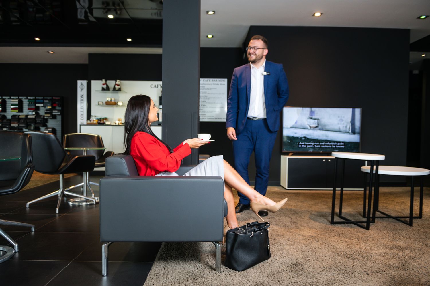 MINI Fleet Specialist talks to customer who is seated and enjoying a cup of tea about the different Business offers available at Bavarian MINI