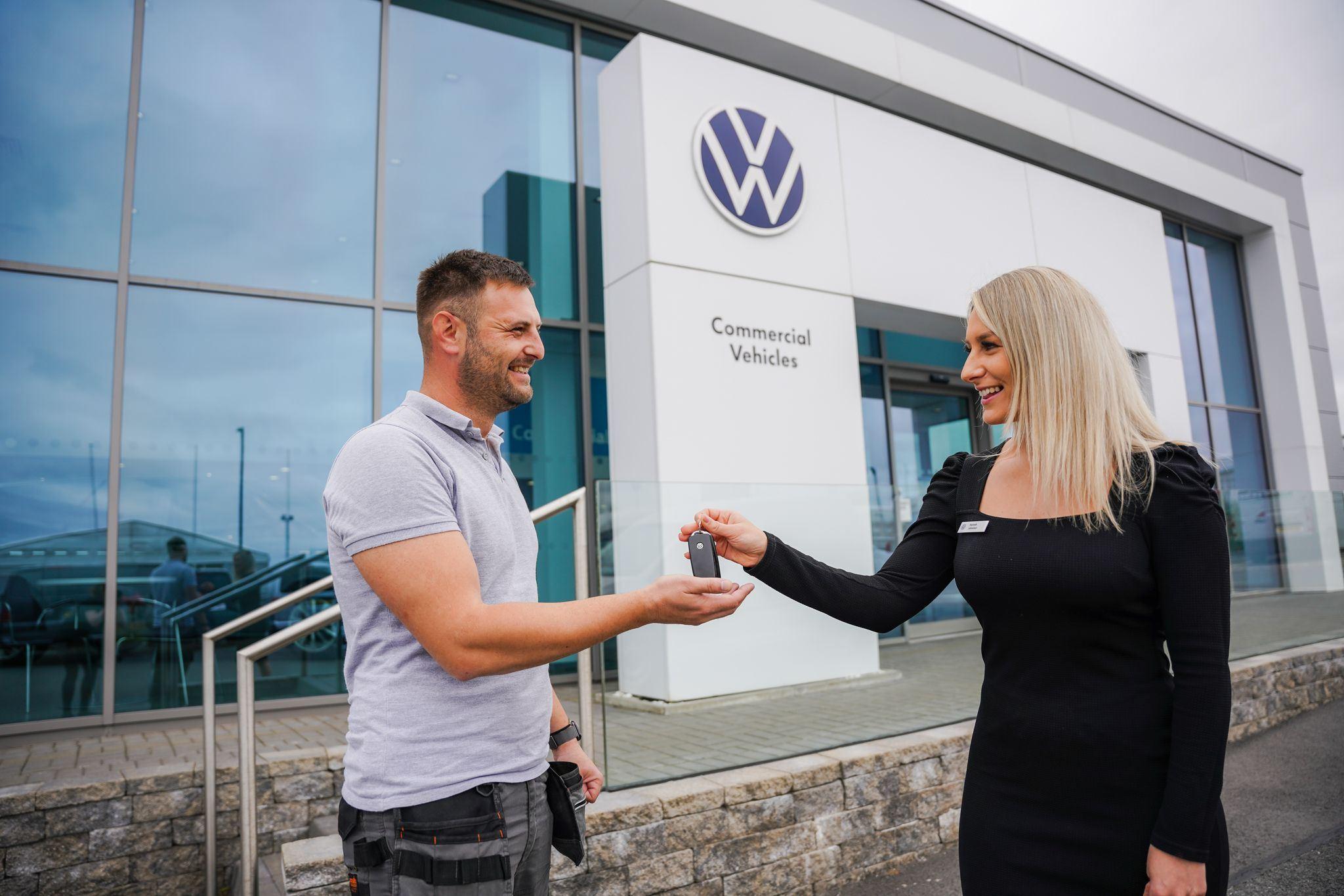 Volkswagen Service Advisor hands over vehicle keys to customers at the entrance of Agnew Van Centre