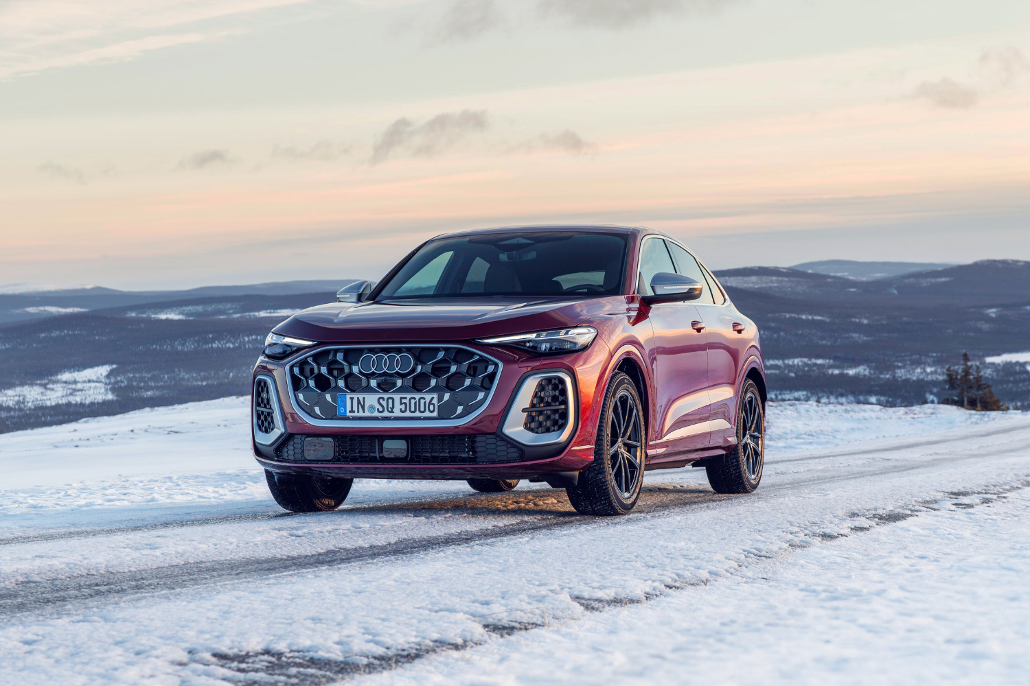 The newly updated Audi SQ5 Sportback in Grenadine red metallic parked on top of a snowy mountain.