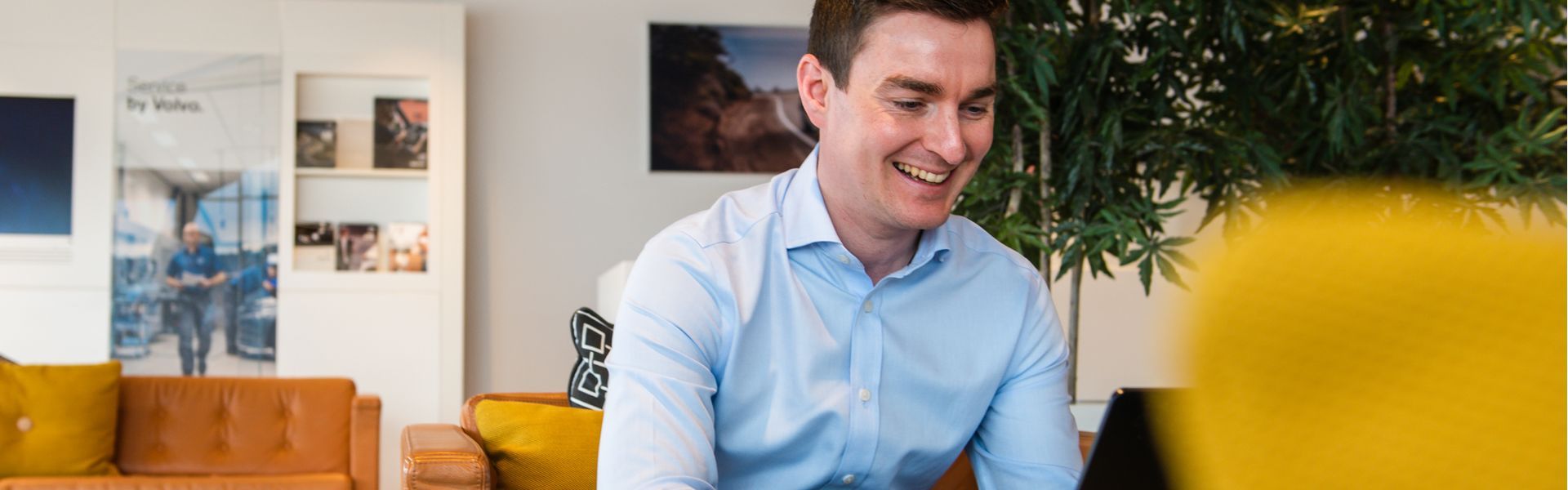 Customer smiles while reading about GAP Insurance on laptop in the Agnew Volvo Belfast showroom