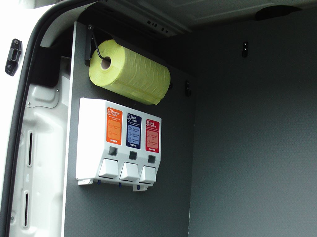 Van interior with wall-mounted dispenser unit and paper towel roll above it.