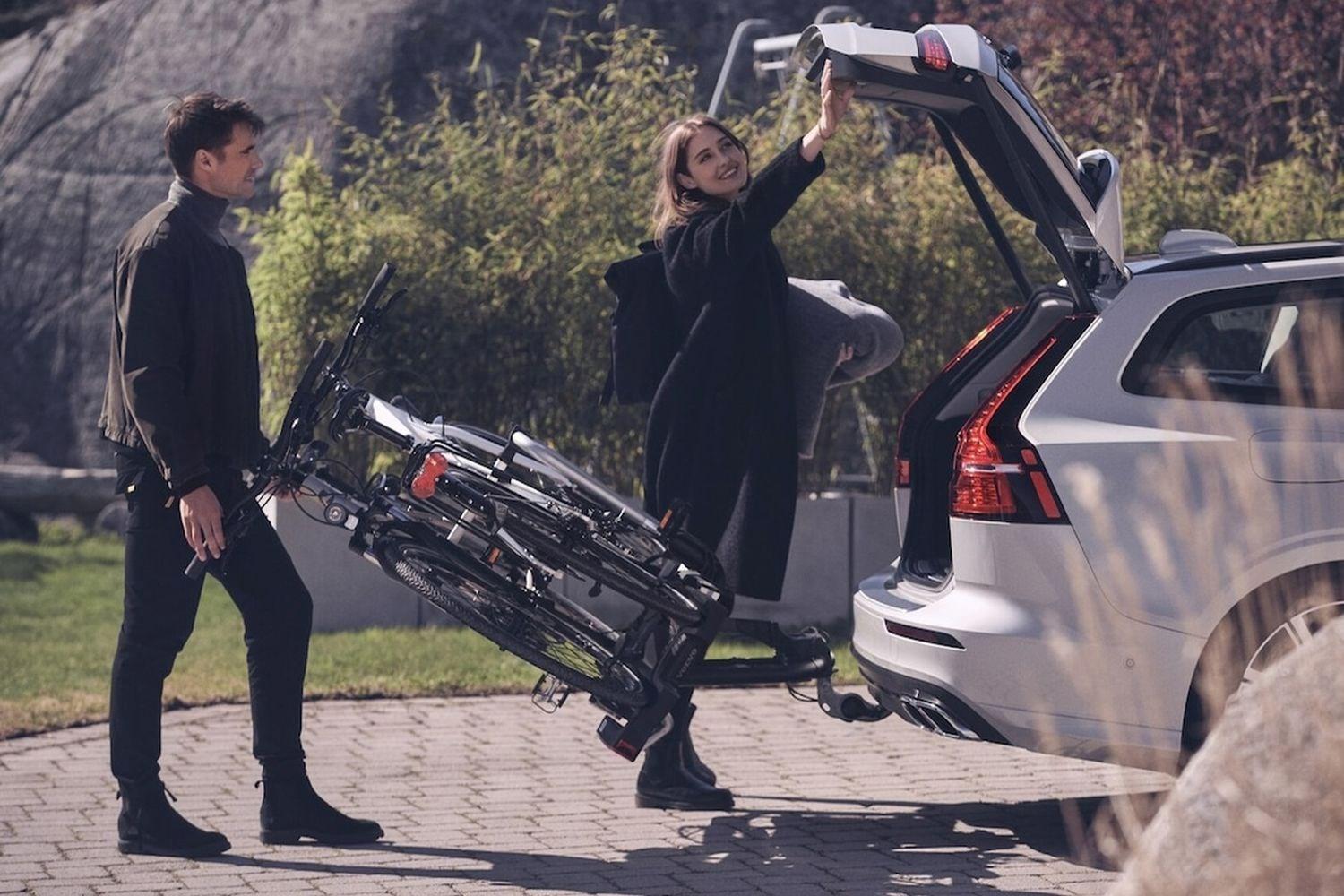 Two people remove bicycle from Volvo XC90 Recharge with Towbar Cycle Pack installed at home.
