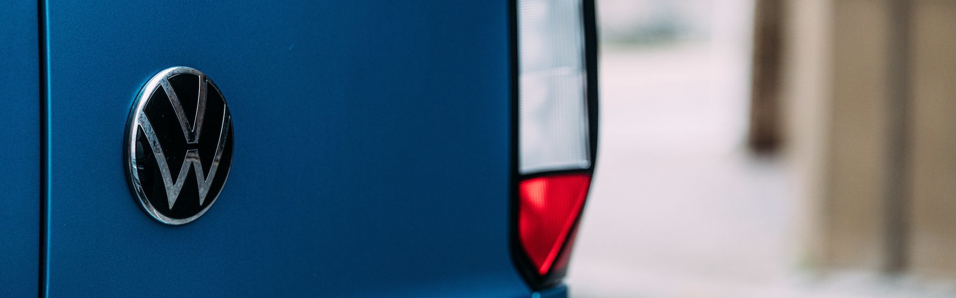 Close up of the Volkswagen logo on the back of a blue Volkswagen Caddy