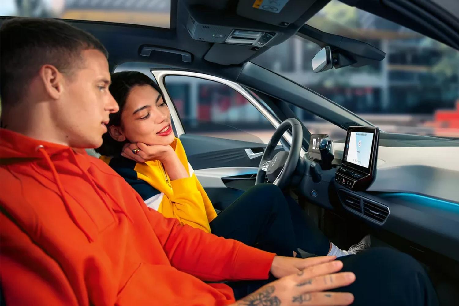 Two passengers look at the built-in sat nav of their Volkswagen Up for directions before they begin their journey.