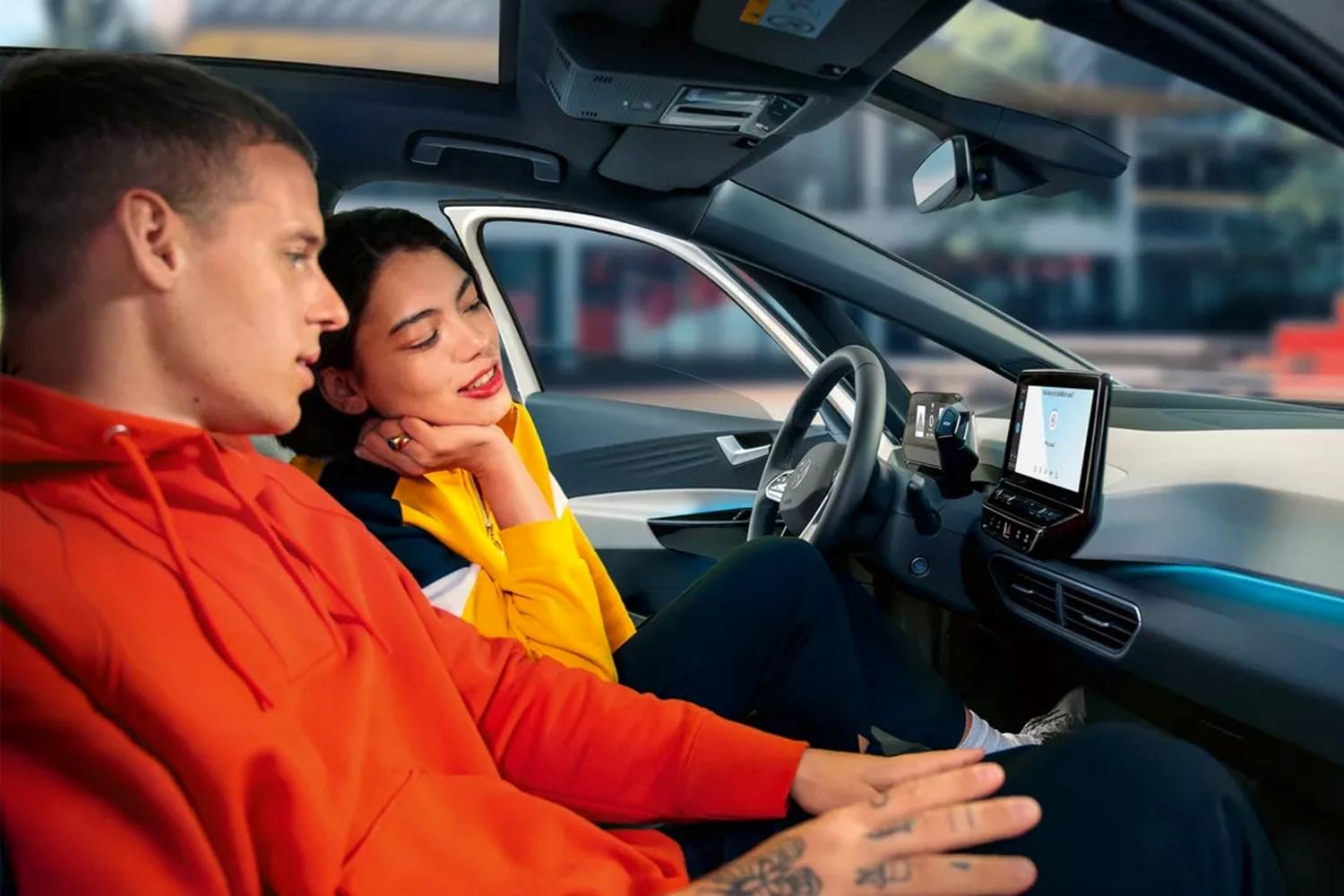 Two passengers look at the built-in sat nav of their Volkswagen Up for directions before they begin their journey.