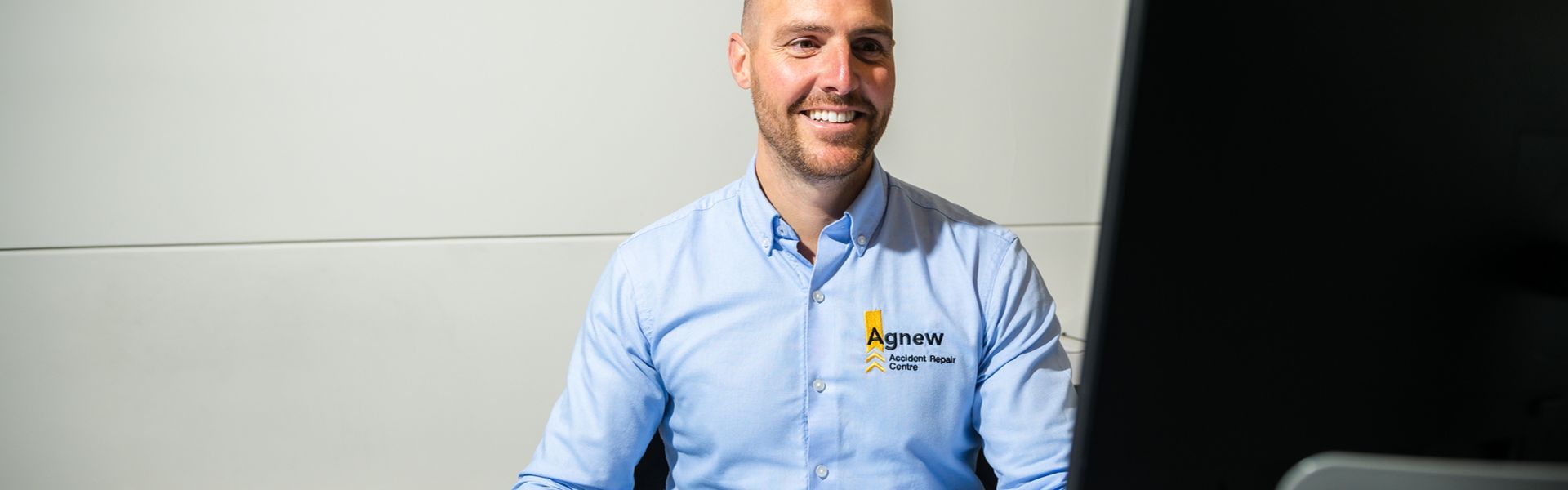 Smiling Agnew Repair Centre Specialist reviews computer for enhancements to customers vehicle.