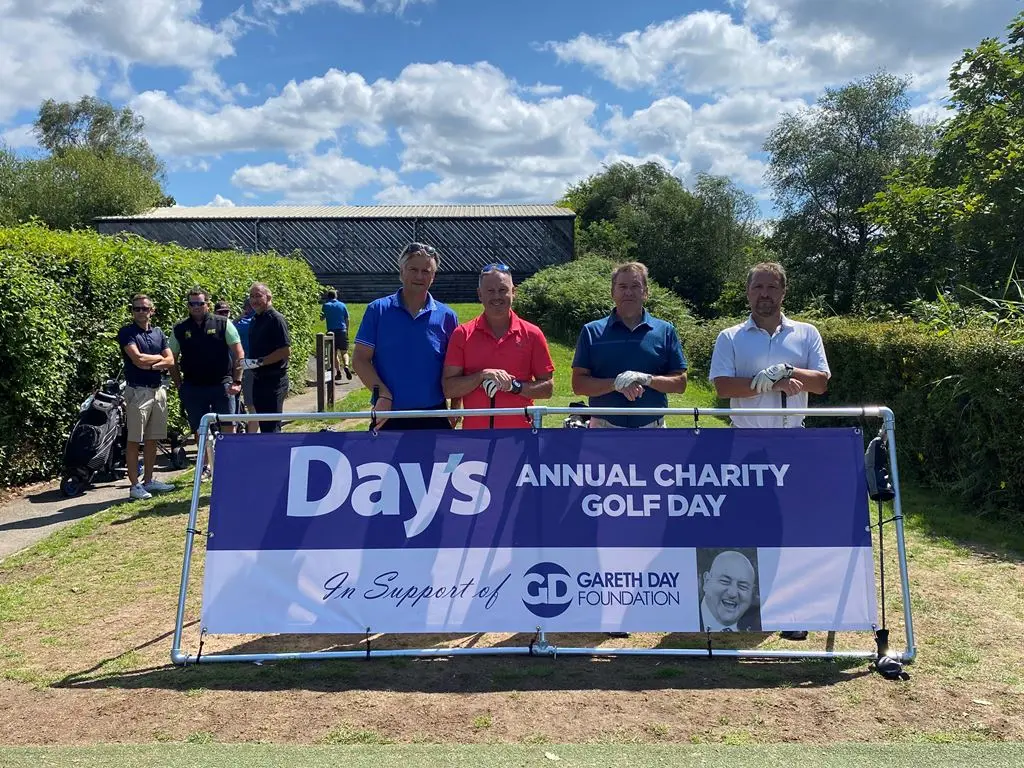 4 Men stood in front of Day's Annual Charity Golf Day banner