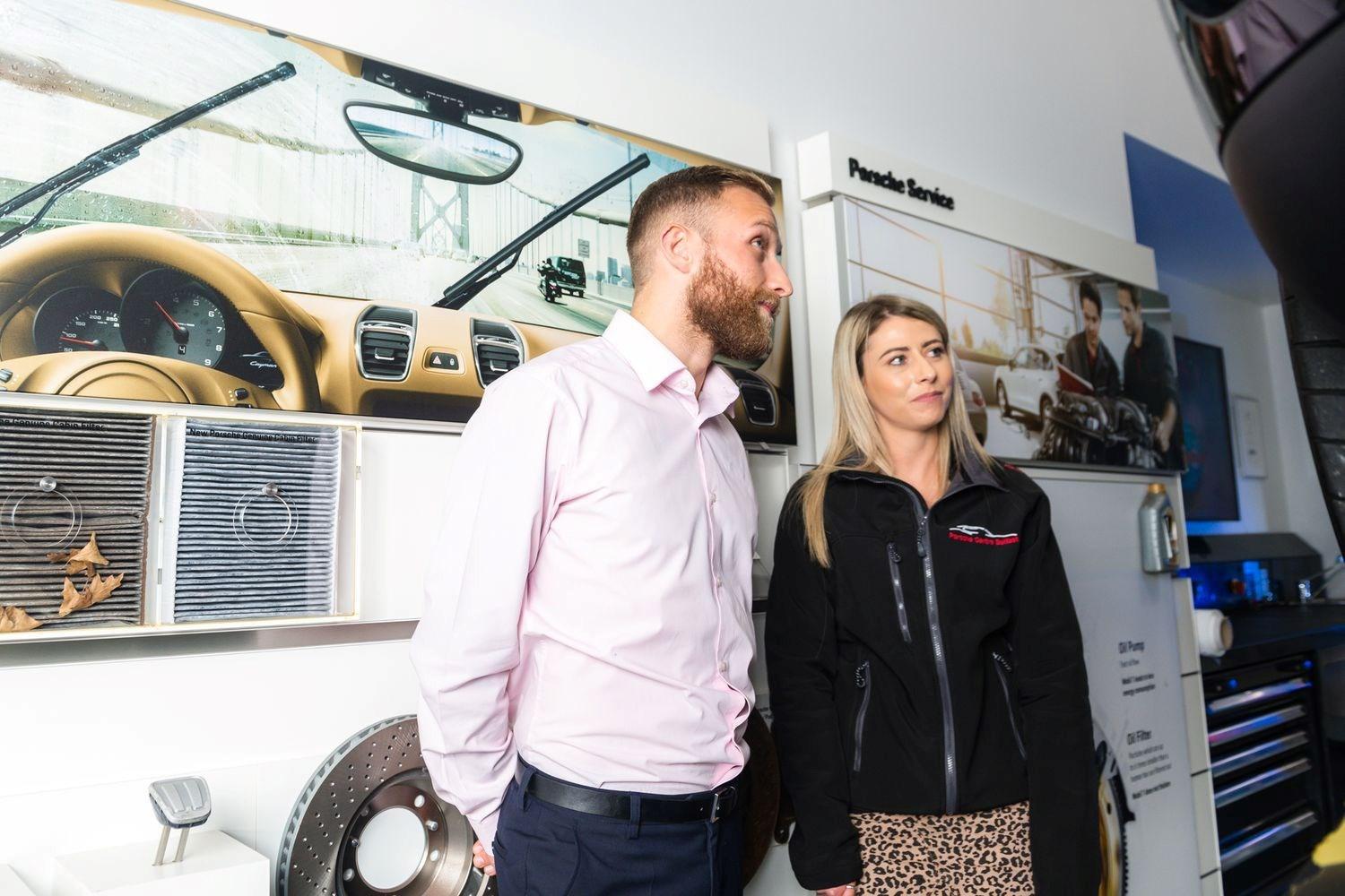 Porsche Centre Belfast Service Specialist talks to customer in the Porsche Centre Belfast showroom about the repairs that will be made to their Porsche.