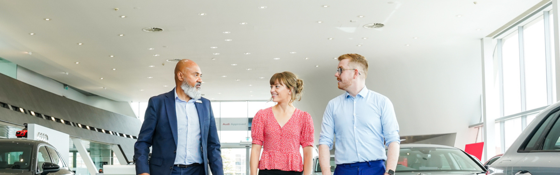 An Audi employee talking to a female and male customer in the Audi showroom.