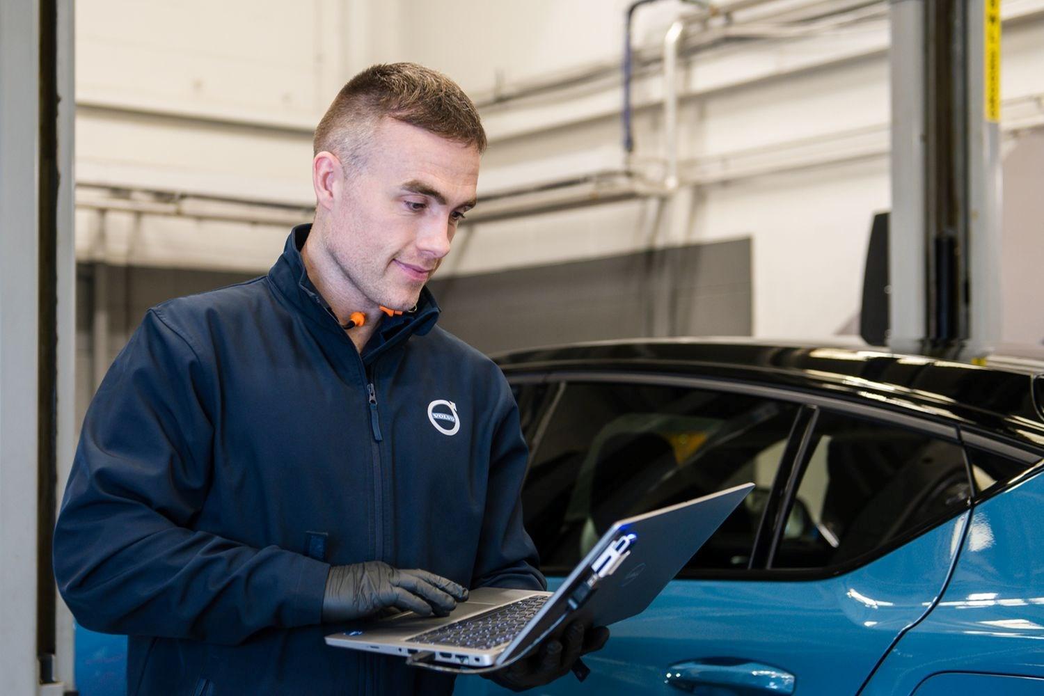 Agnew Belfast Volvo mechanic conducts routine maintenance on used Volvo C40 Recharge with laptop at Volvo repair centre in Belfast, Northern Ireland