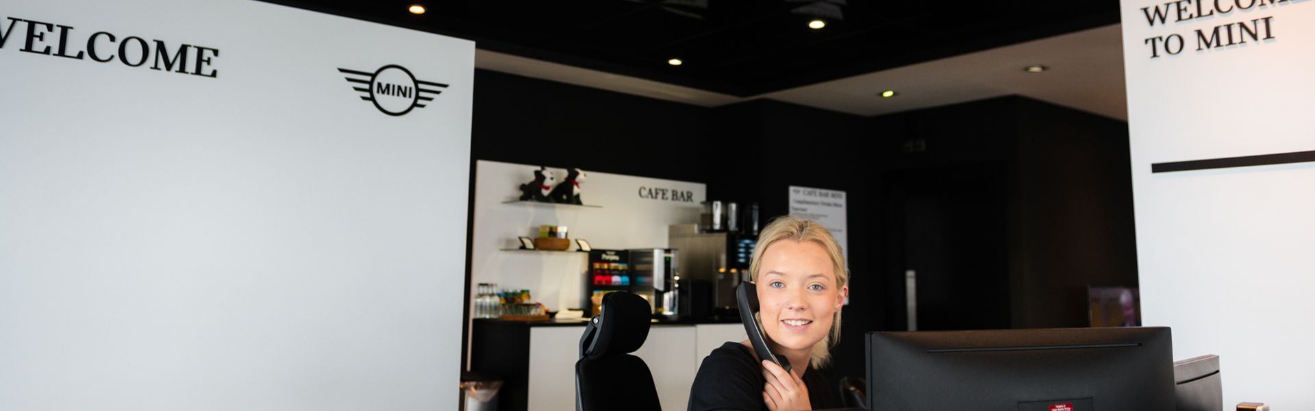 MINI Service Specialist talks to customer on the phone at the reception of Bavarian MINI