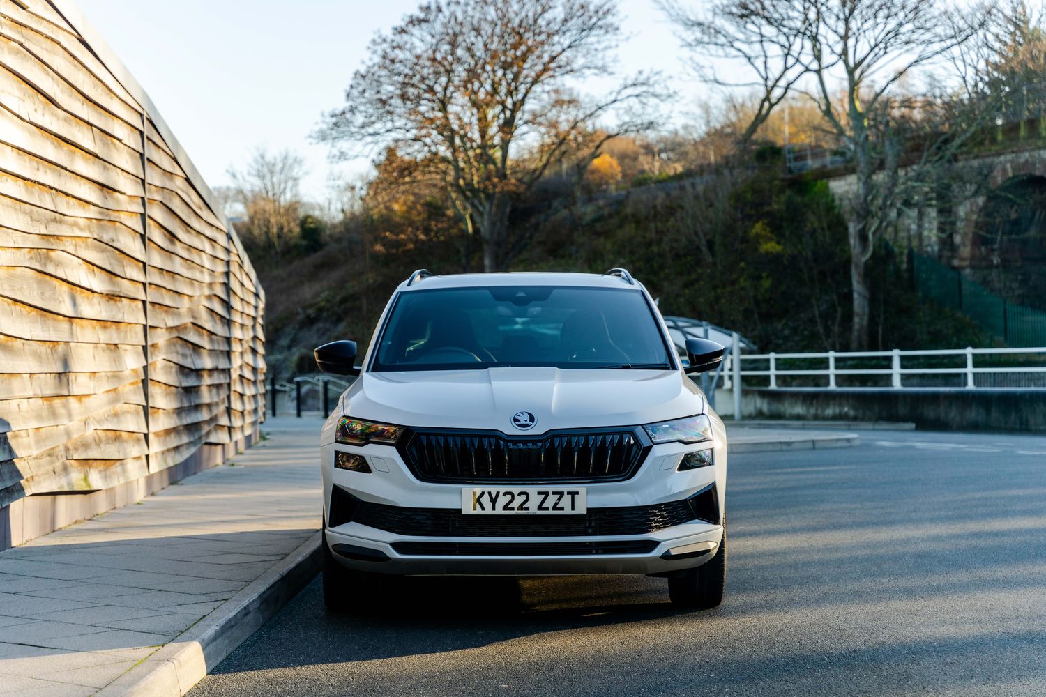 Front view of the new Skoda Karoq. Parked on road, next to fence.