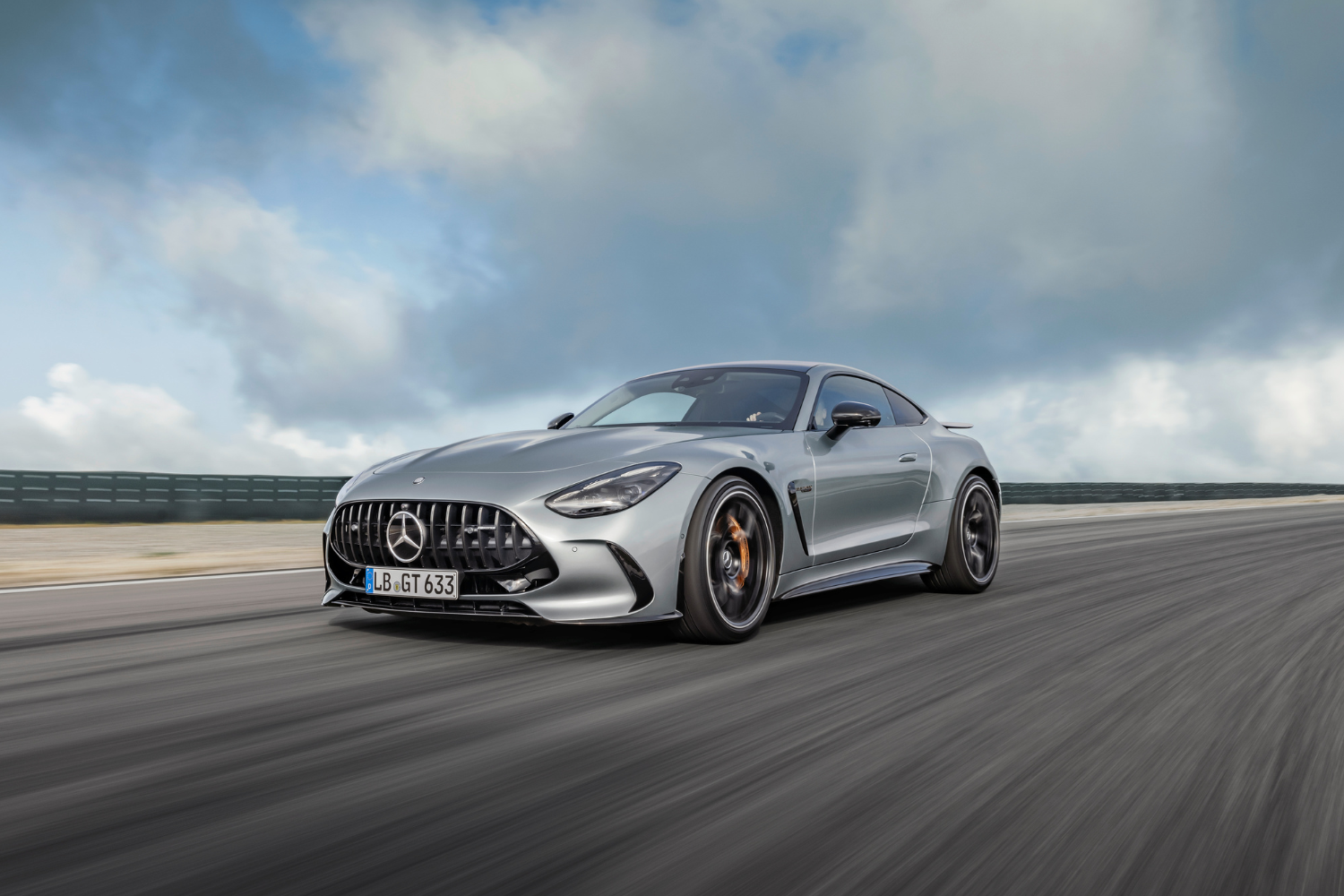 Side view of a silver Mercedes-Benz AMG GT Coupe driving around a race track.