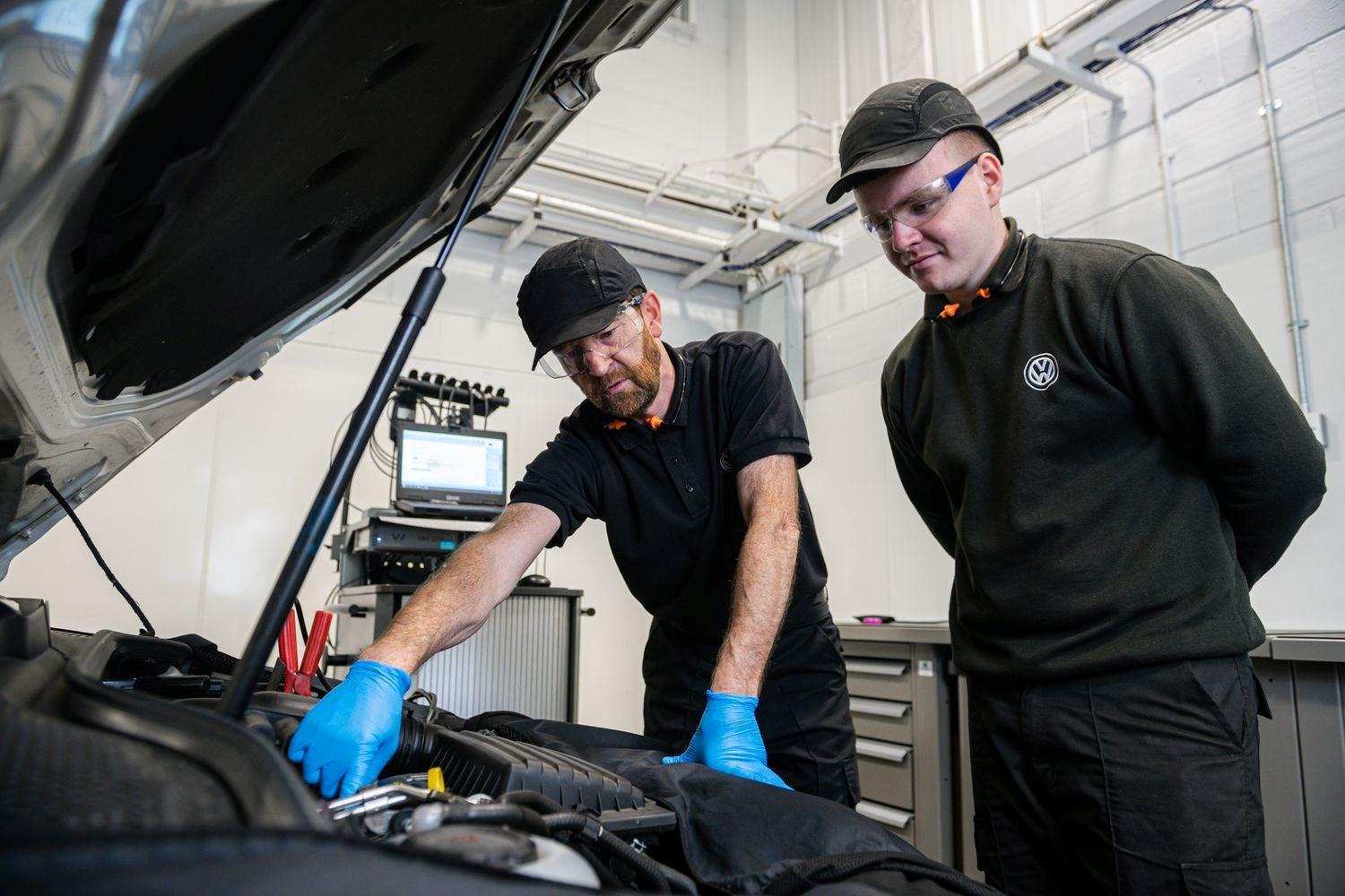 Two Volkswagen Service Specialists check under the hood of a used Volkswagen Golf for servicing and maintenance at the Volkswagen Approved Accident Repair Centre, Agnew Volkswagen Belfast