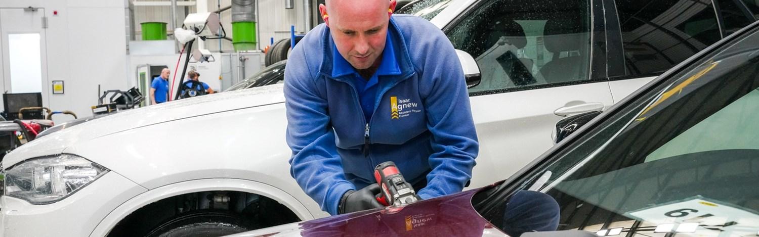 Agnew Repair Centre Technician makes small cosmetic repair to the side of a vehicle at Agnew Repair Centre workshop.