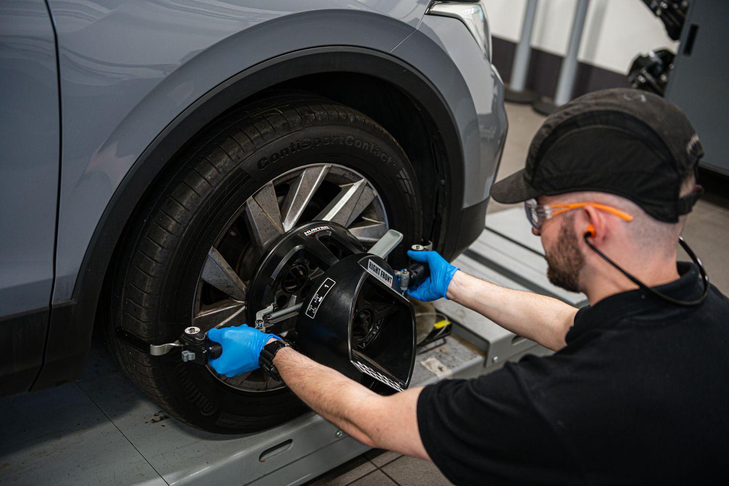Volkswagen Technician inspects wheel of Volkswagen vehicle during repair work