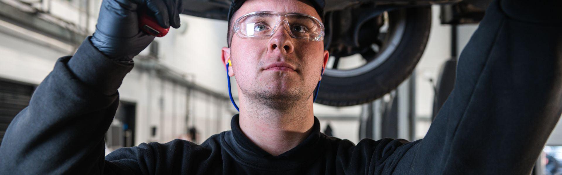 Volkswagen Service Specialist checks underneath a car during routine maintenance at the Volkswagen Approved Accident Repair Centre, Agnew Volkswagen Belfast