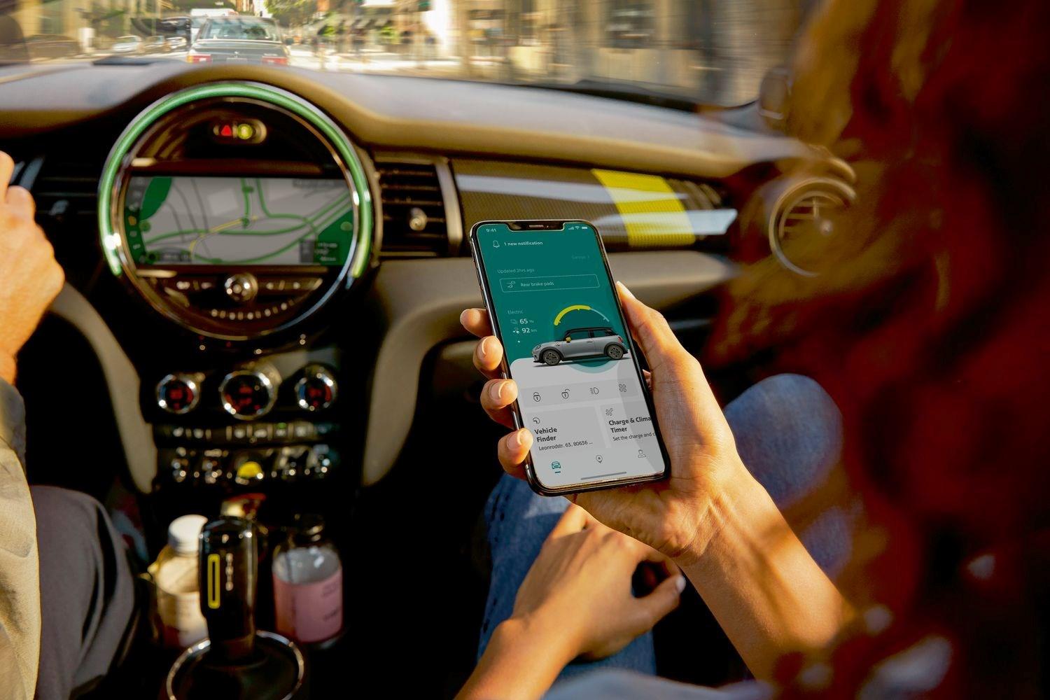 Interior view of the new MINI 3-Door Hatchback, close-up of passenger using the MINI Connected Application on their phone to find out more about their MINI vehicle