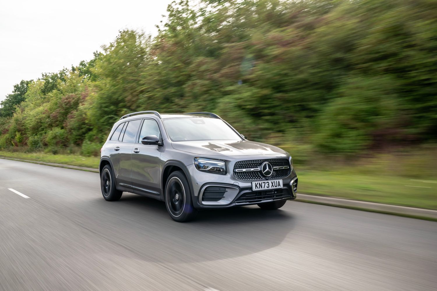 A silver Mercedes Benz driving.