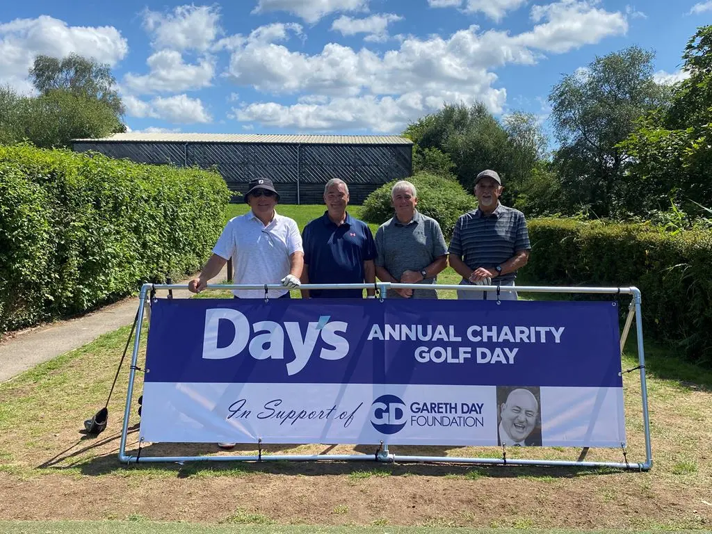 4 Men stood in front of Day's Annual Charity Golf Day banner
