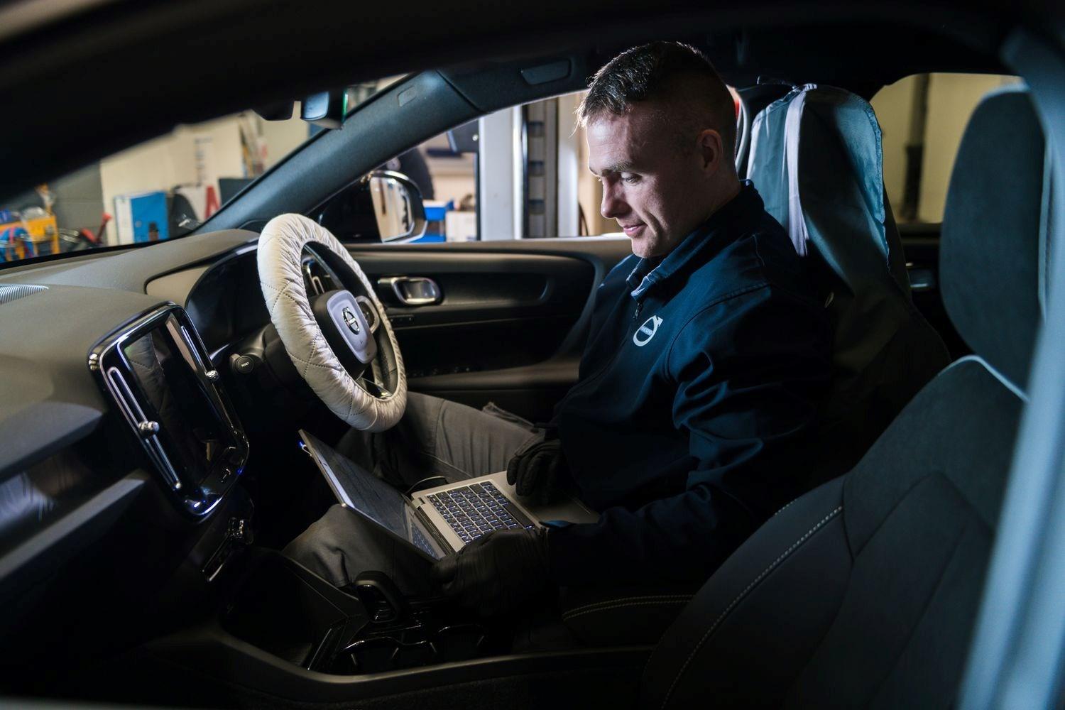 Volvo Service Specialist connects laptop to interior of Volvo vehicle for software upgrade