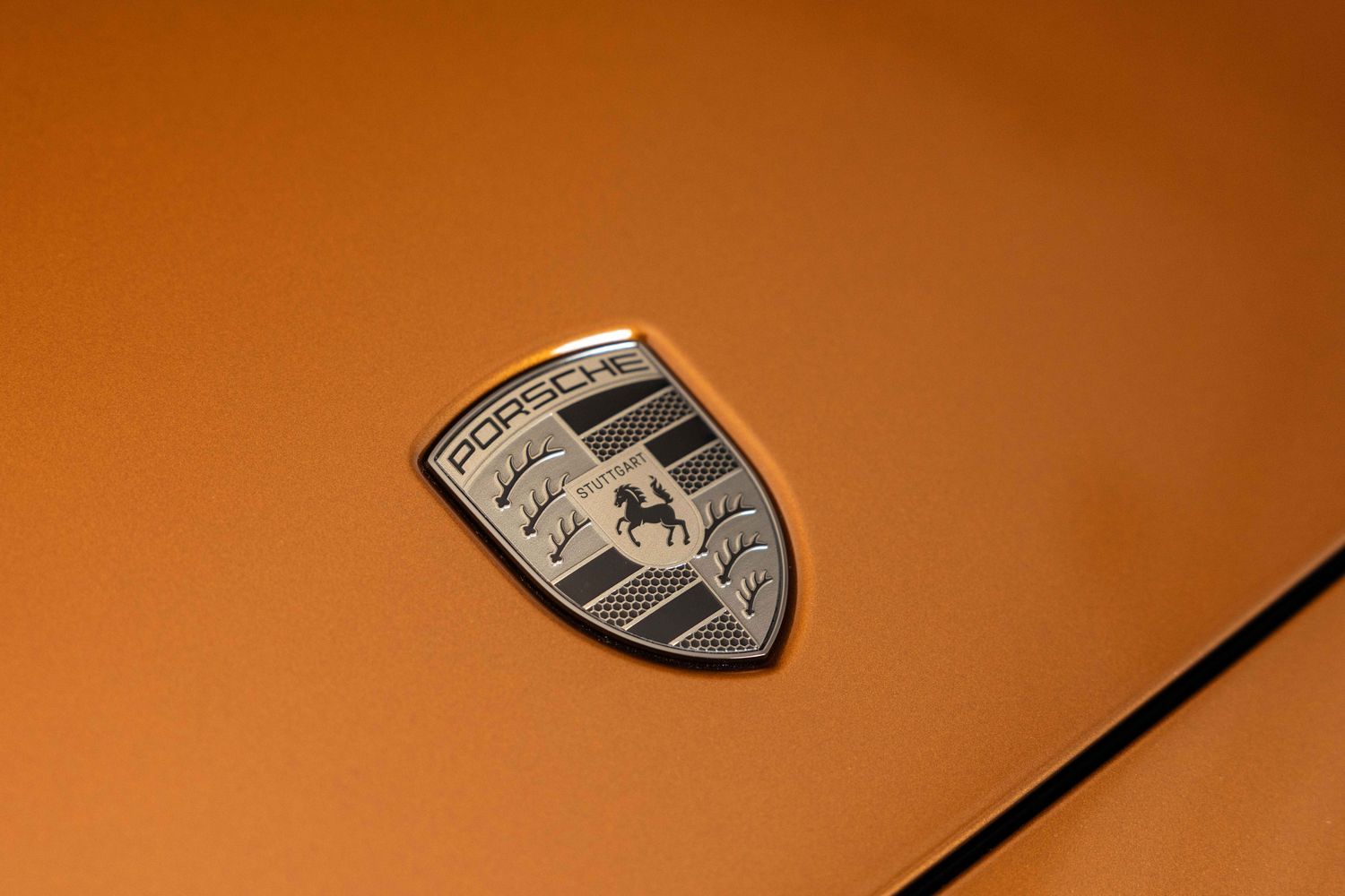 Exterior view of the new Porsche Panamera in orange, close-up of front Porsche badge