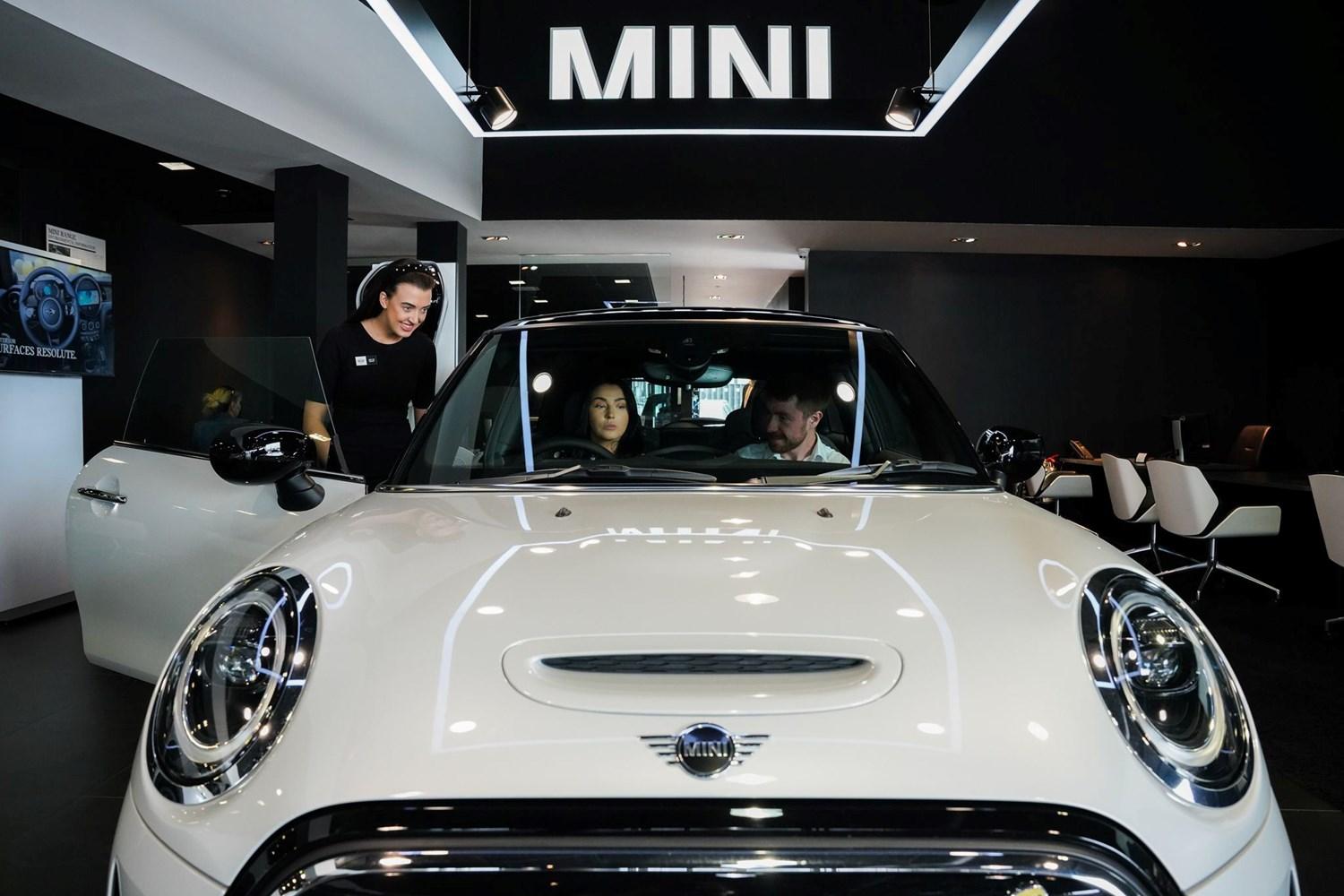 MINI Sales Specialist speaks to customers about the key features of the MINI Cooper as they sit inside of the vehicle at the Bavarian MINI Showroom