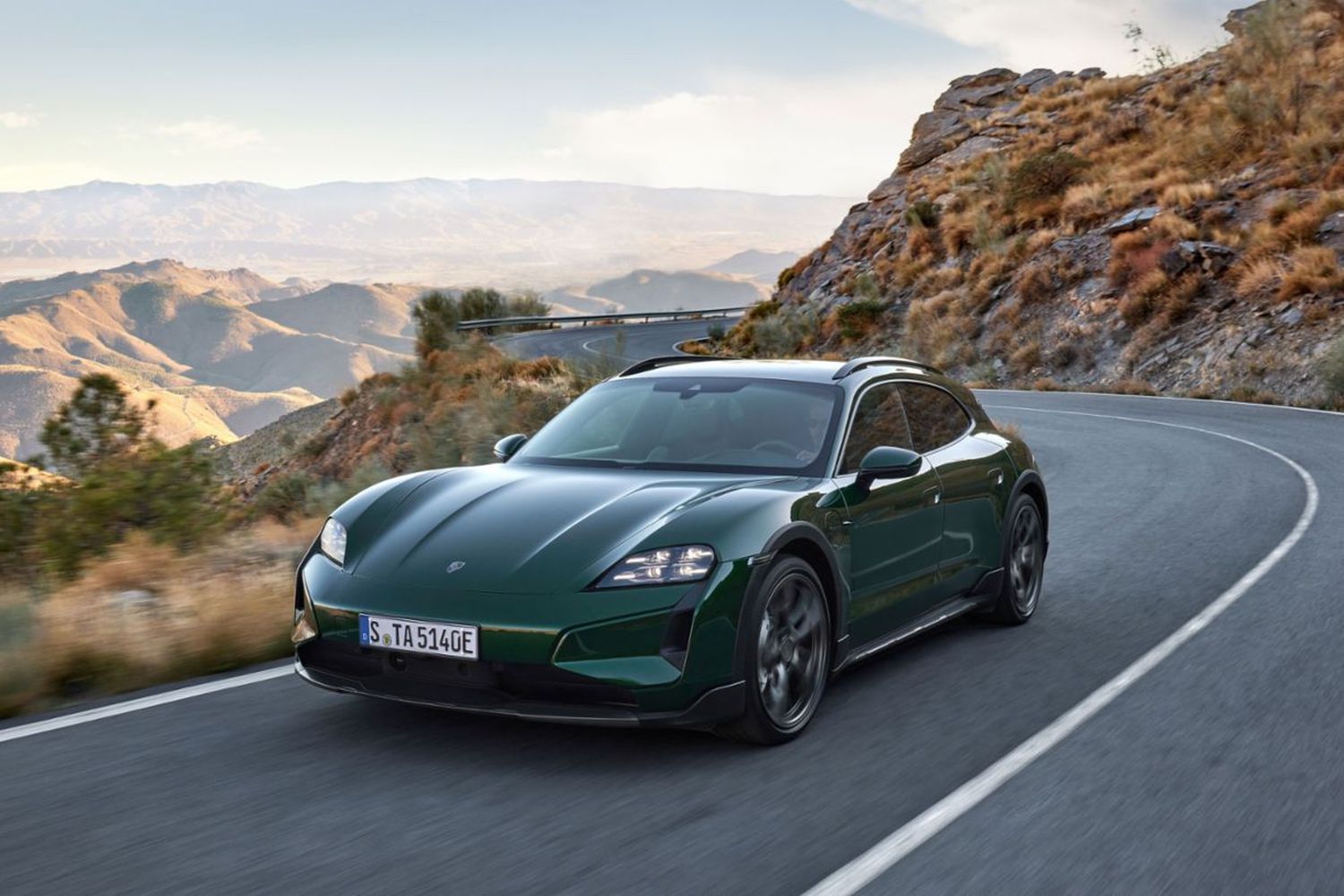 Front view of the new Porsche Taycan Cross Turismo in green, driving along desert road