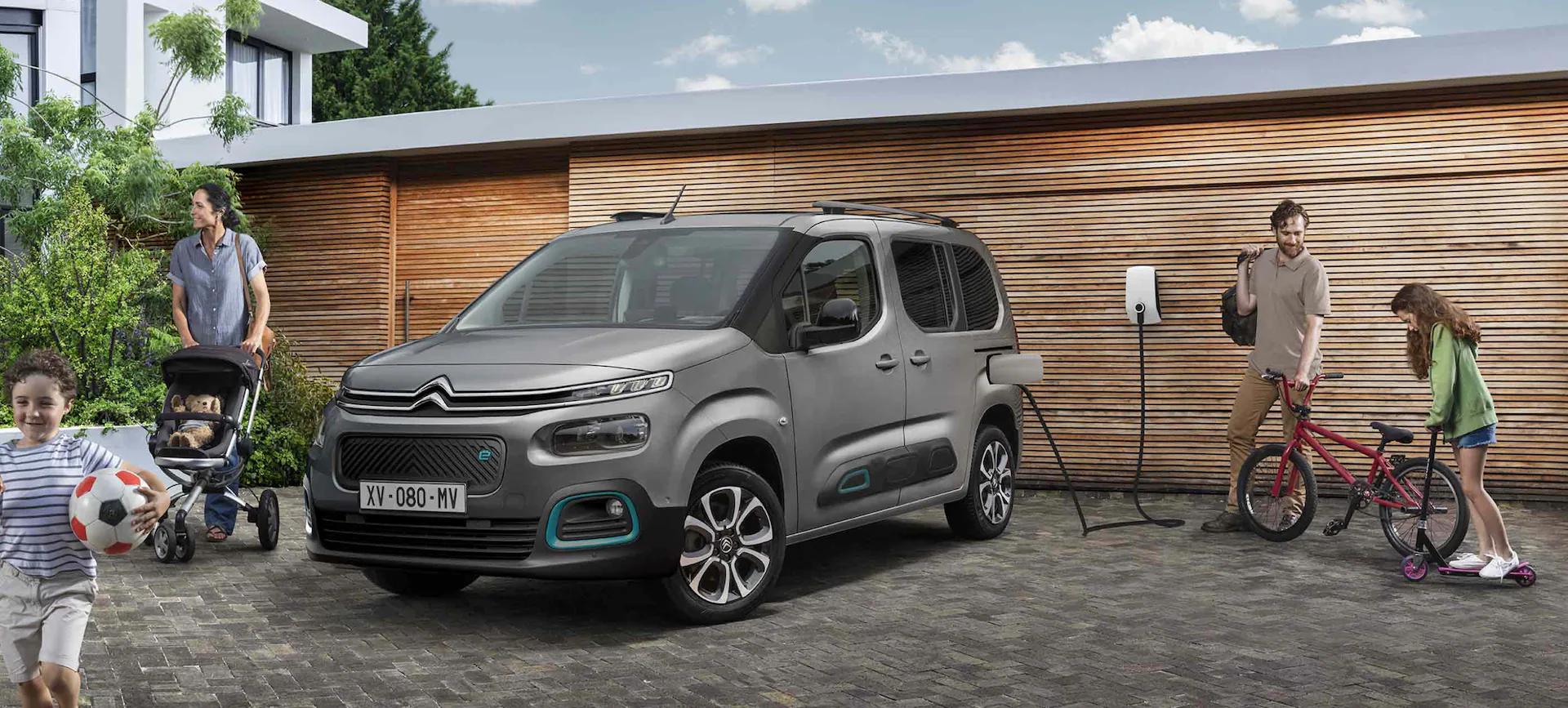 Citroen Berlingo charging at a modern house, with a family around