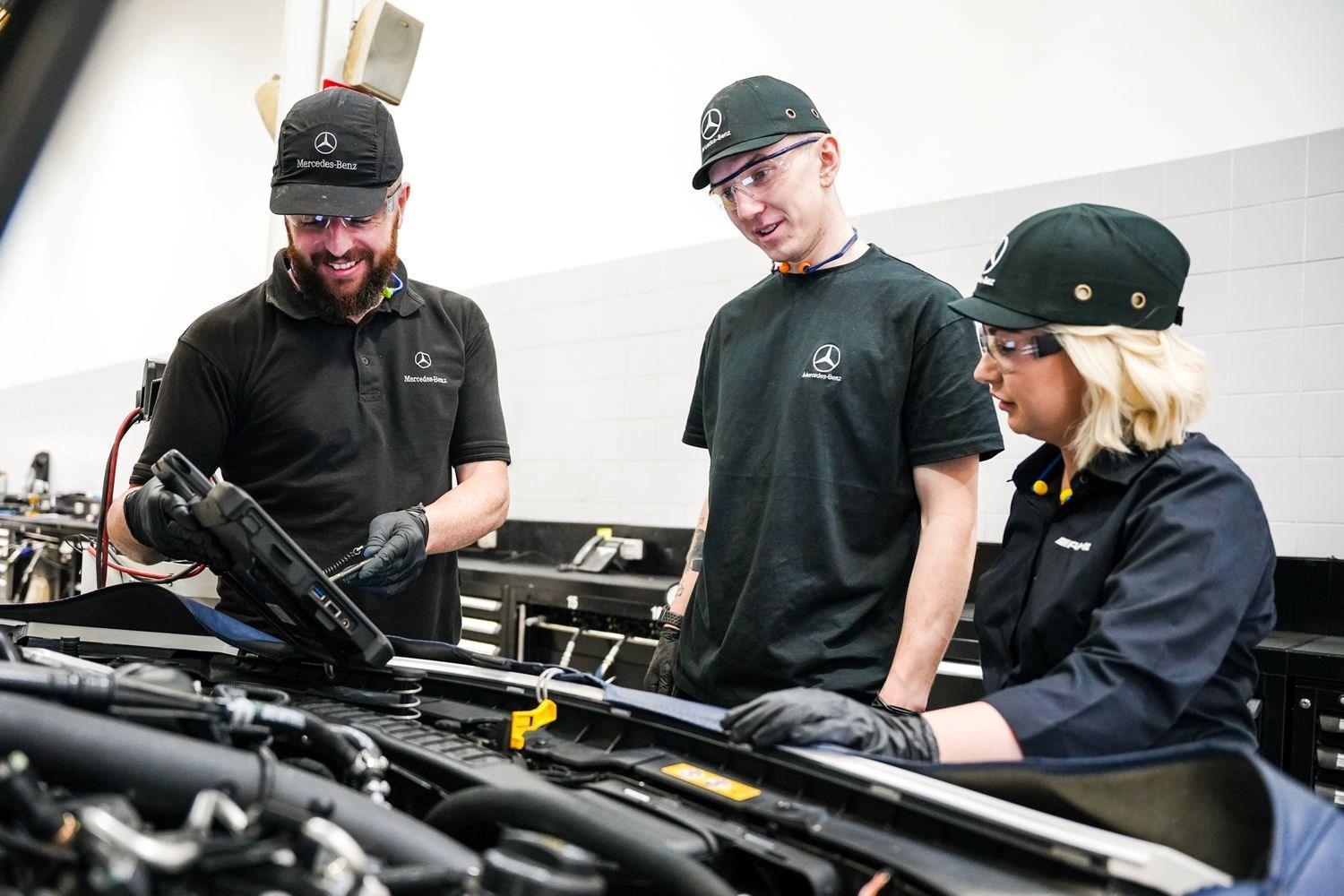 Three Mercedes-Benz technicians discuss the electrical issues of a Mercedes-Benz vehicle on tablet during MOT inspection