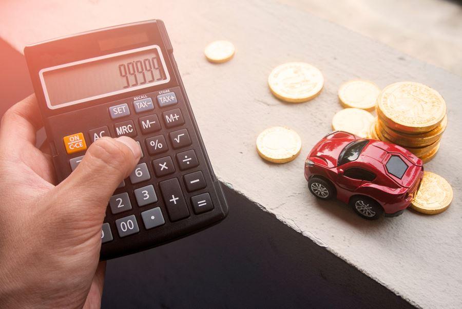 Calculator with 99999 on it, with mini red car and some coins in the background